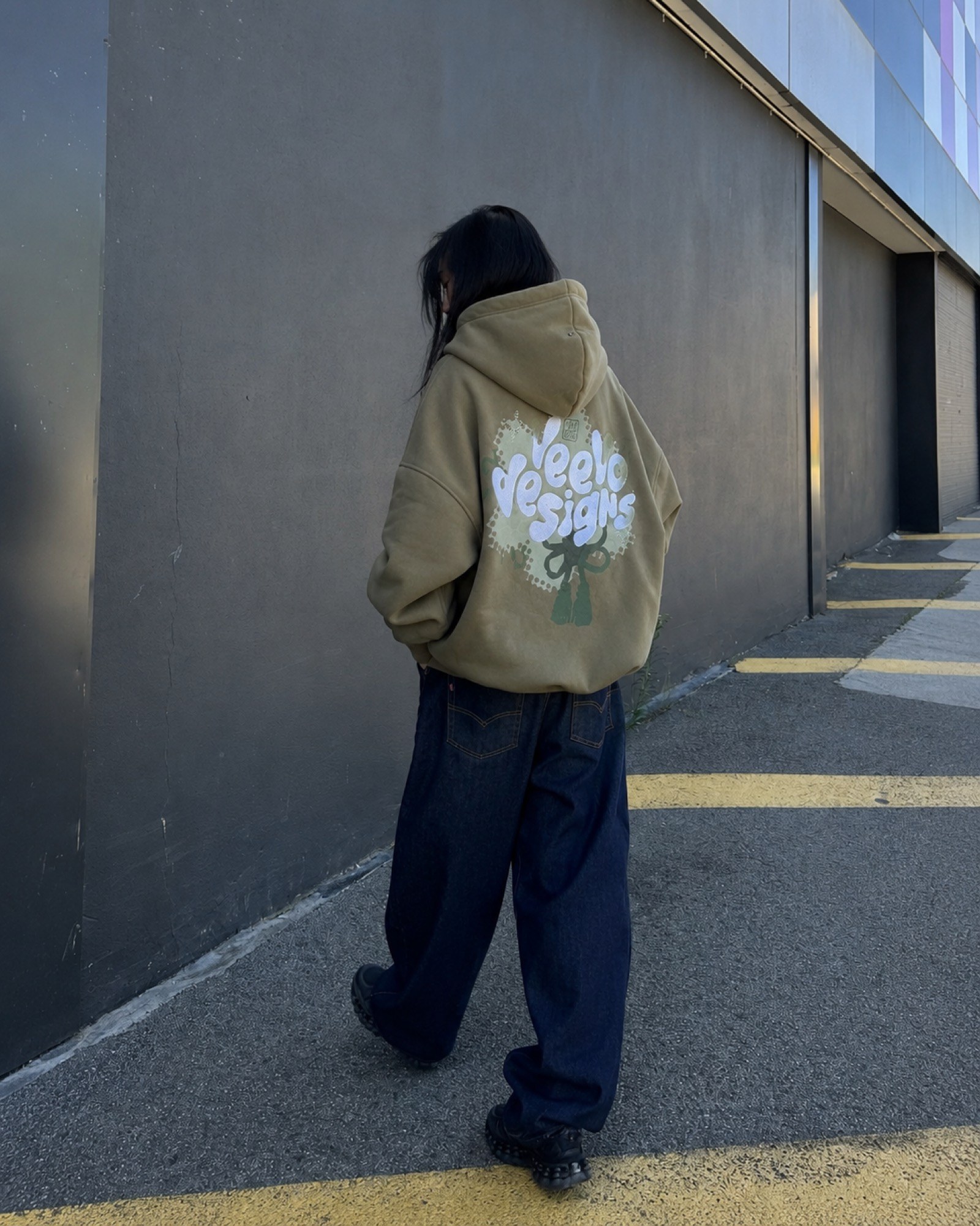 Model wearing a sage custom hoodie with a large printed back graphic